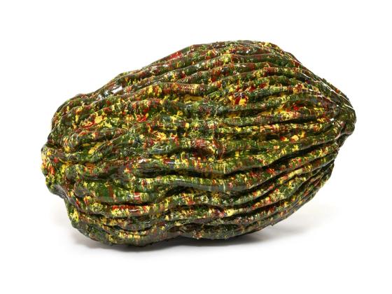 Abstract ceramic sculpture with an elongated, ridged form covered in glossy green, yellow, and red splattered glazes